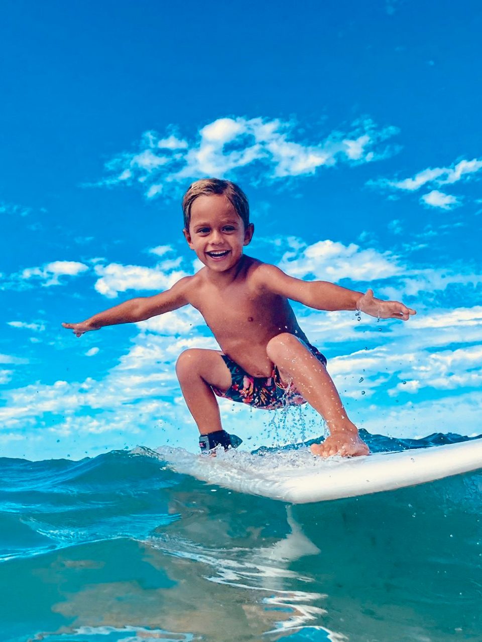 a young girl riding a wave on a surfboard in the water