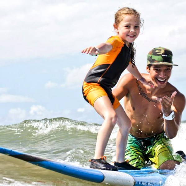 a young girl riding a wave on a surfboard in the water