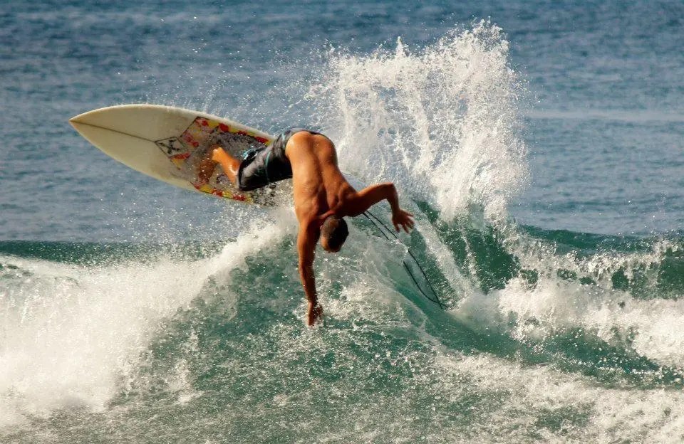 Surfer performing an aerial maneuver on a wave in the ocean.